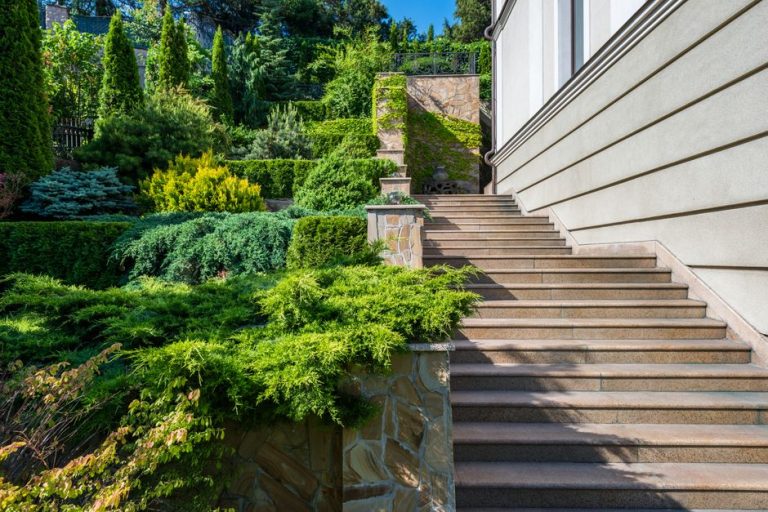 Tiered stone retaining walls with lush landscaping on a sloped backyard in Fresno CA