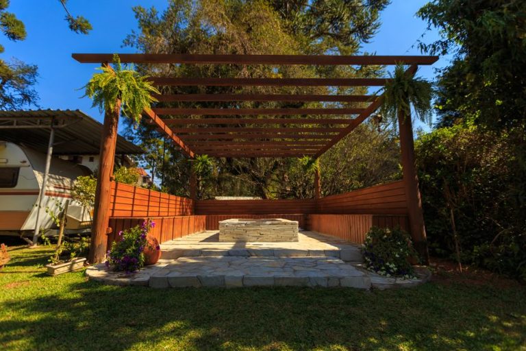 Wooden pergola over a stone patio in a sunny backyard — pergola builder serving Clovis and Fresno, CA